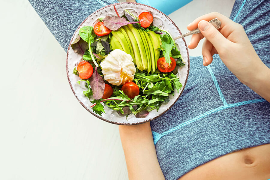 frau-sportlich-isst-salatteller-biohacking-ernaehrung